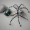 Beaded wire spider featuring a detailed silver-patterned bead, black legs, and shimmering accent beads for a mystical handmade décor piece.